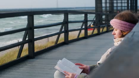 woman reading a book by the ocean