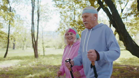 alegre pareja de ancianos abuelo, abuela entrenando caminata nórdica, corriendo en el parque de verano