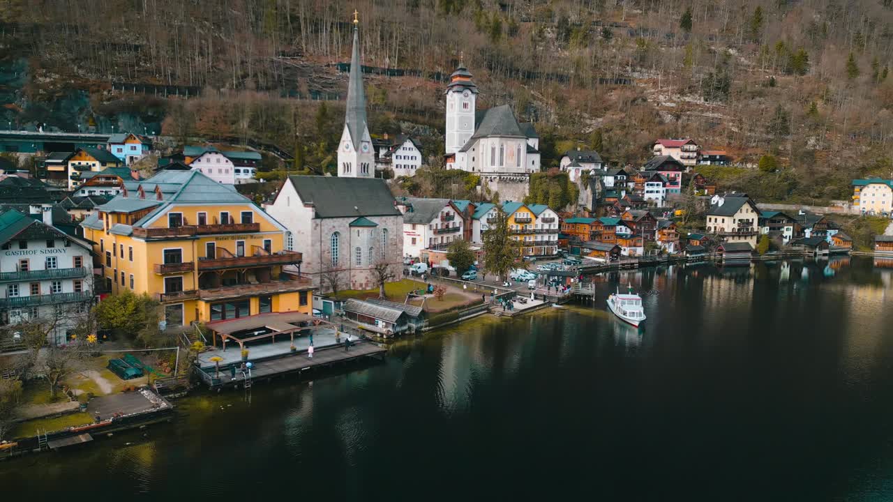 Droneoptagelse i mellemhøjde: Etablerende 4K filmisk materiale af Hallstatt, Østrig, omgivet af de østrigske alper. Når optagelsen panorerer væk, ses mere af den ikoniske landsby.