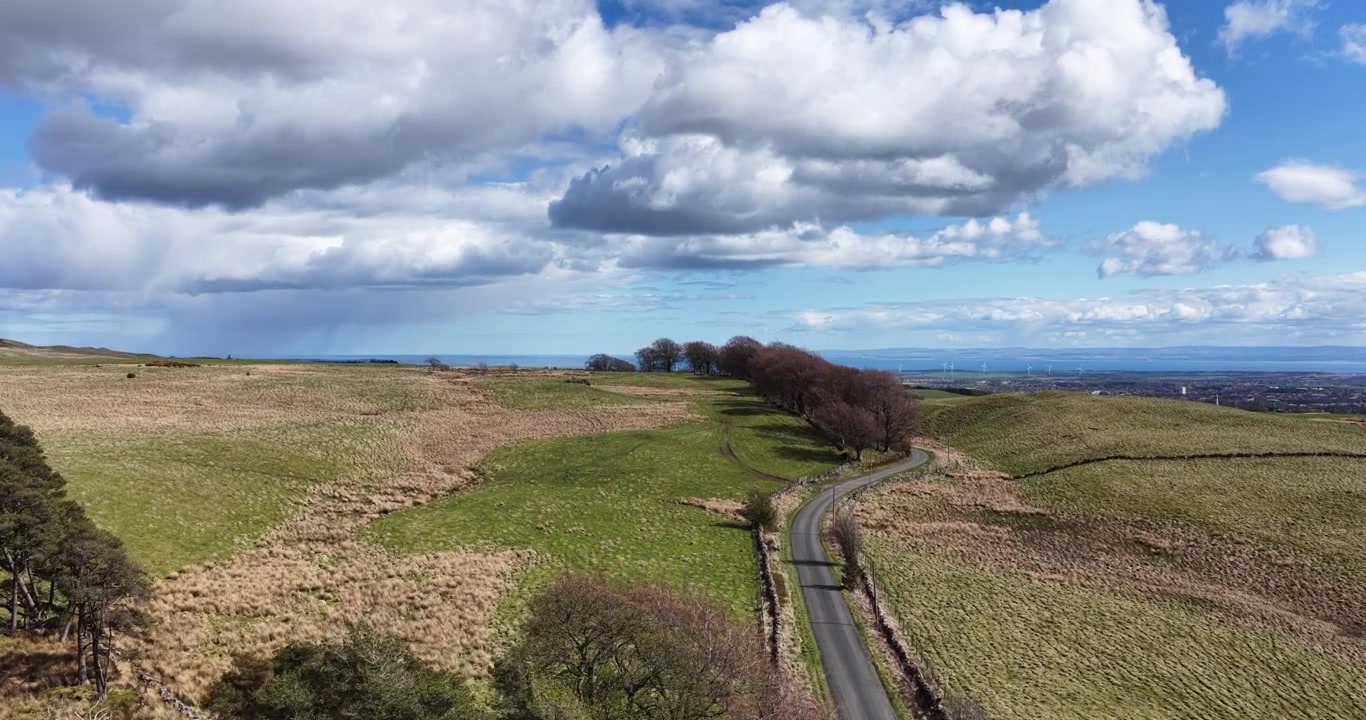 Luftfoto, der følger en afsidesliggende, enkeltsporet vej i det skotske landskab. Billedet er taget i Lomond Hills, Fife, og som optagelsen skrider frem, stiger kameraet for at afsløre Fife i baggrunden