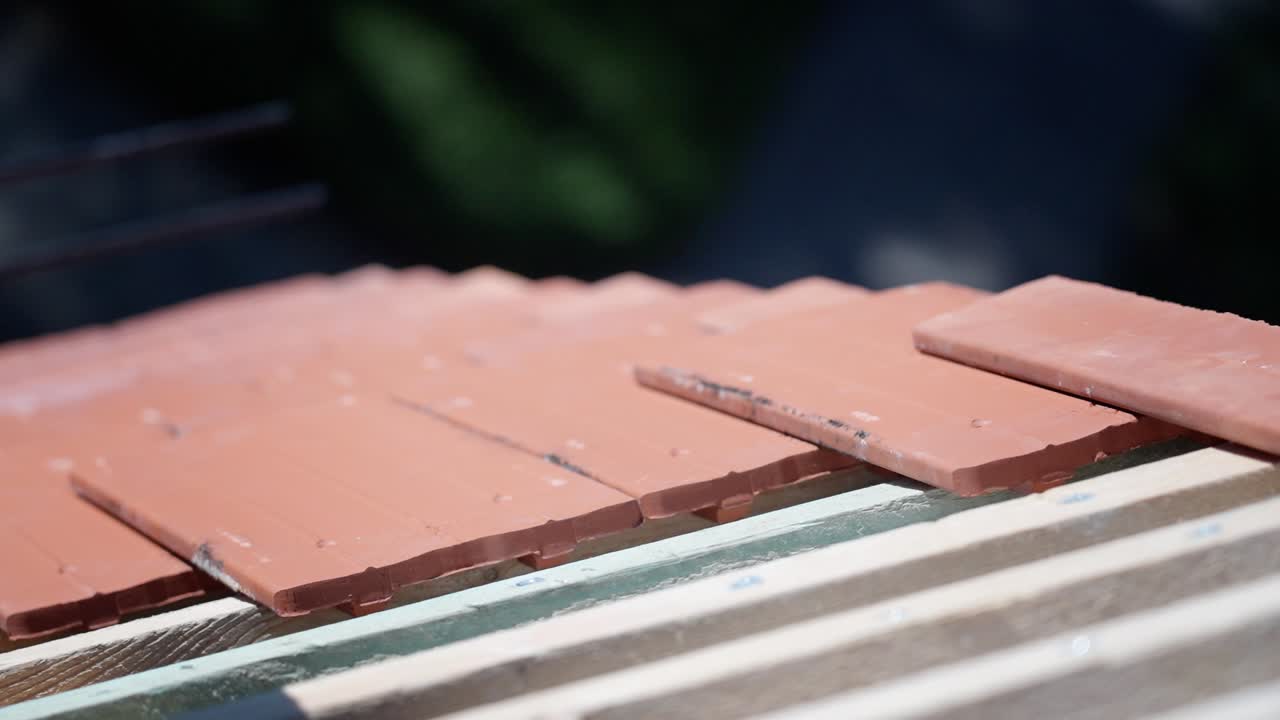 Worker laying red roof tiles during a restoration project