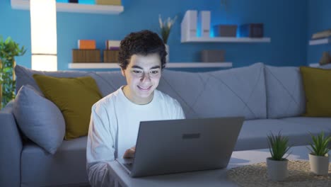 un niño lindo y adicto a la tecnología jugando juegos en la computadora portátil en casa.