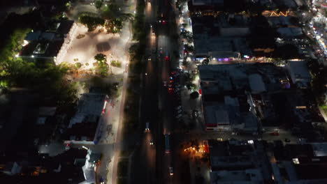 High-angle-view-of-road-intersection.-Tilt-up-reveal-long-straight-busy-street-and-panoramic-view-of-city-at-night.-Cancun,-Mexico