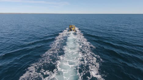 retrolavado de un barco de pesca navegando en el mar azul profundo cerca de la isla de los pájaros en la patagonia, argentina