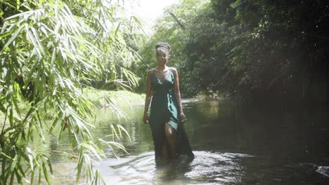 woman in a river in the caribbean walks towards the camera in slow motion