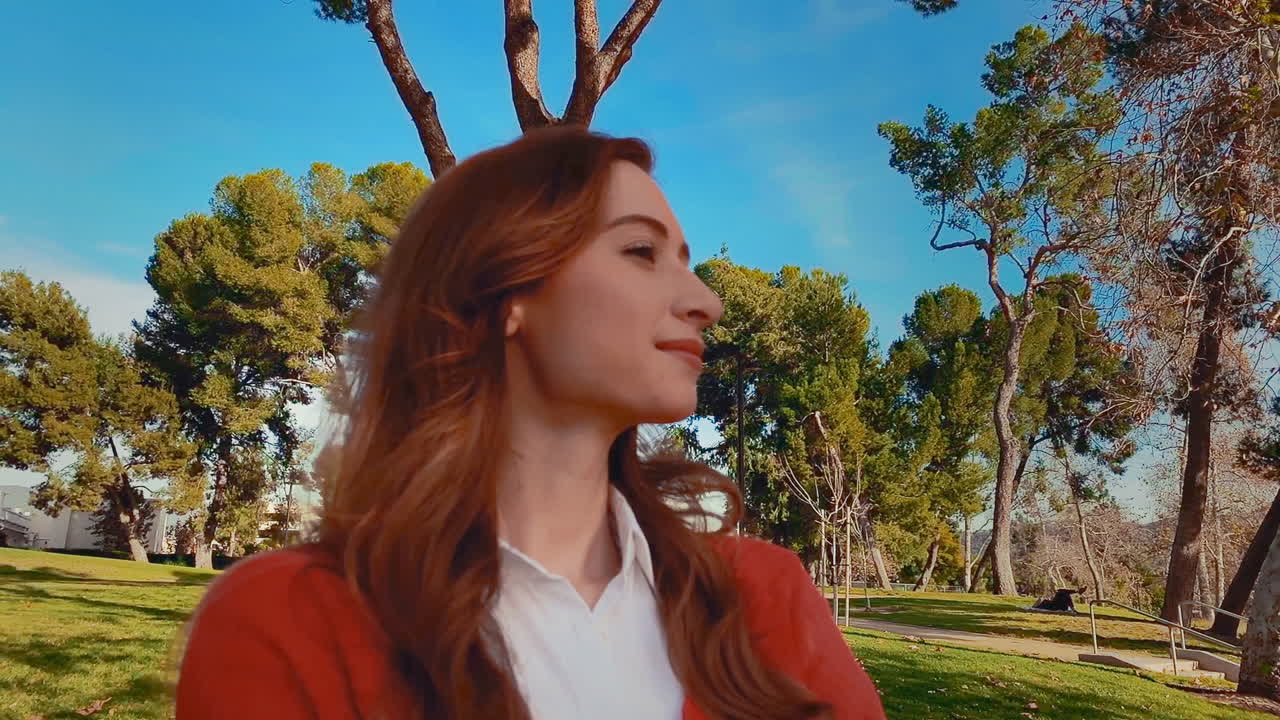 una feliz, atractiva, joven, mujer caucásica en el parque, mirando lejos de la cámara - relajada, serena, mentón arriba, segura de sí misma