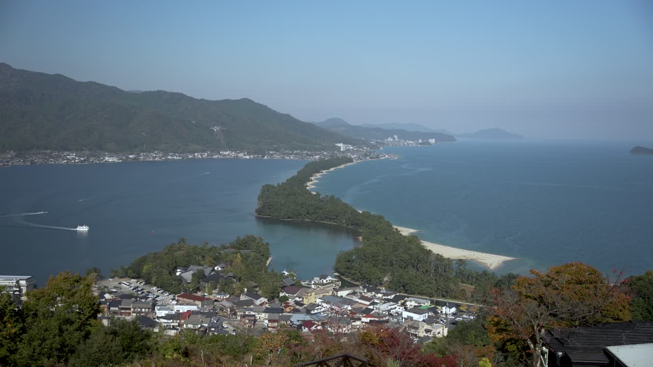 Panoramic view of Amanohashidate Sandbar dividing Miyazu Bay in Japan, with mountains and forest in the background on a sunny day