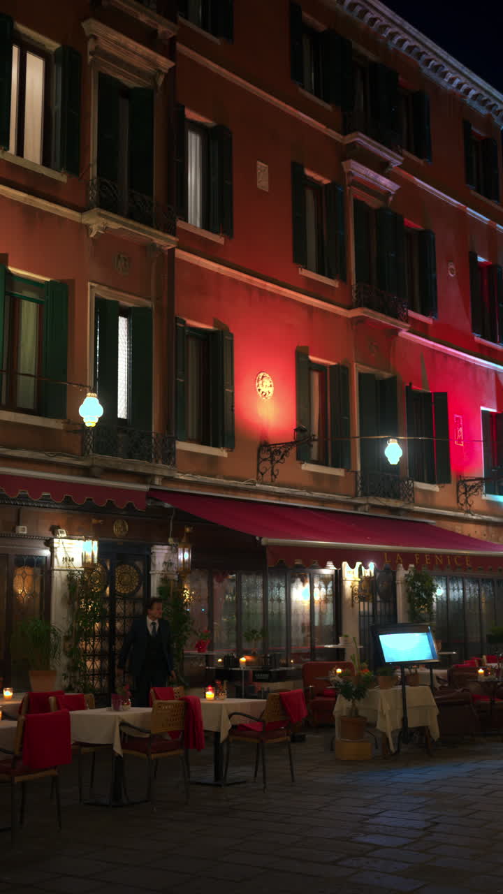 View of lit candles on set tables at a restaurant in the city in the evening . Vertical