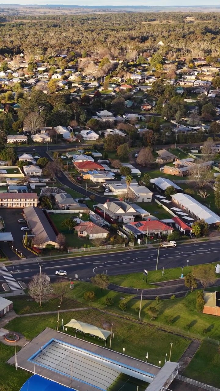 Ripresa aerea con drone dall'alto di una cittadina suburbana con case e piscina in Australia.