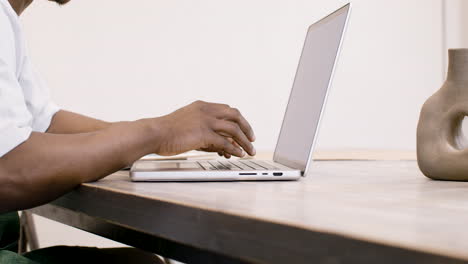 empleado americano en delantal sentado frente a la computadora portátil y escribiendo en el teclado 1