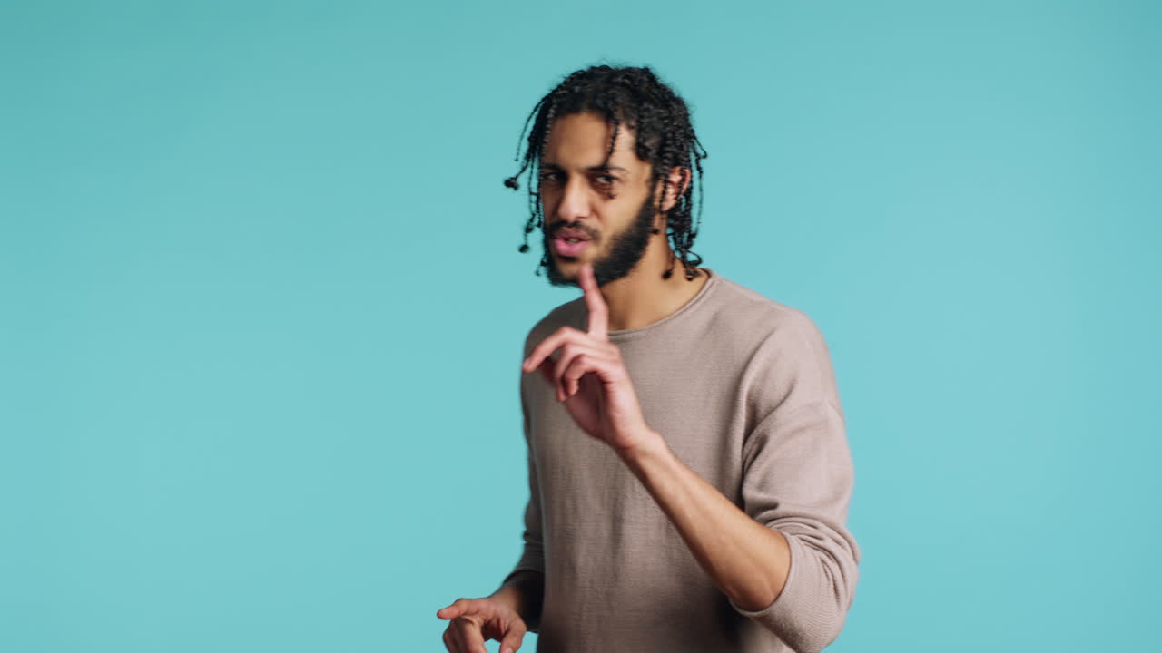 Annoyed man doing shushing hand gesturing, irritated by noise, studio background