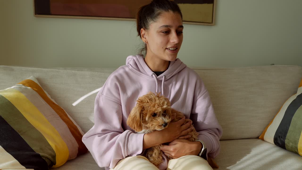 Giovane donna che accarezza e coccola il suo tenero cucciolo su un divano