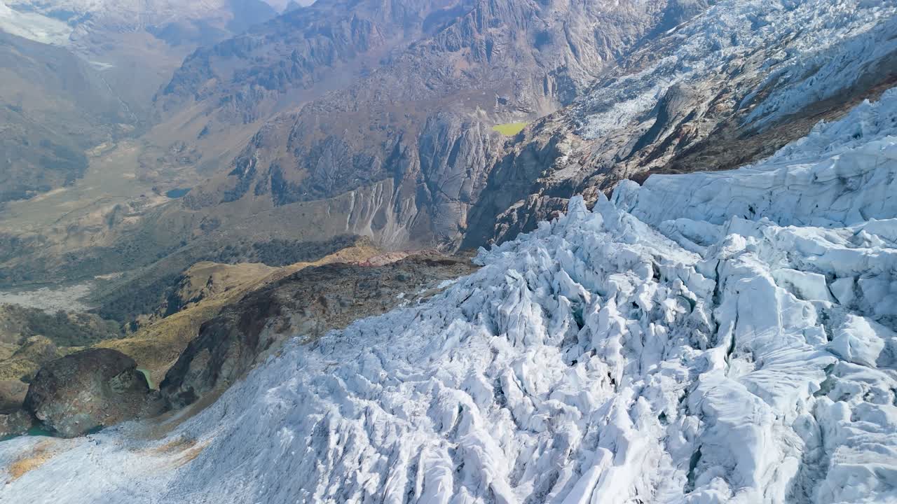 A spectacular aerial drone shot flies alongside the heavily crevassed and jagged ice formations of the glacier on Mount Mateo in the high Andes of Peru, revealing its raw texture