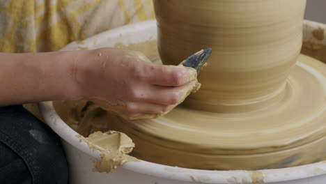 Handheld-high-angle-close-up-shot-of-using-a-scraper-to-work-on-the-surface-of-a-potter-vase