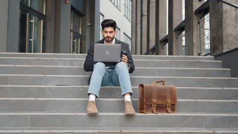 hombre de negocios trabajando en una computadora portátil al aire libre en las escaleras