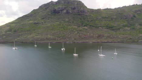 Ocean-Coastline-Aerial-Drone-footage-of-white-yachts-,-pacific-ocean-with-rocky-mountain-on-the-background