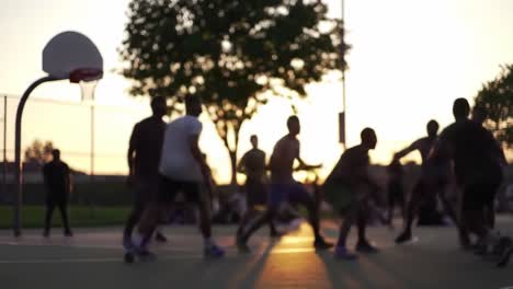 golden sunset illuminating basketball players competing on urban playground, capturing dynamic energy and camaraderie of friends playing together during evening recreational game