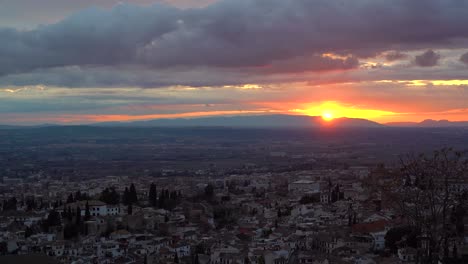 bright orange sun setting over cityscape of granda, spain