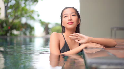 close-up of an attractive woman relaxing along the side of a posh pool