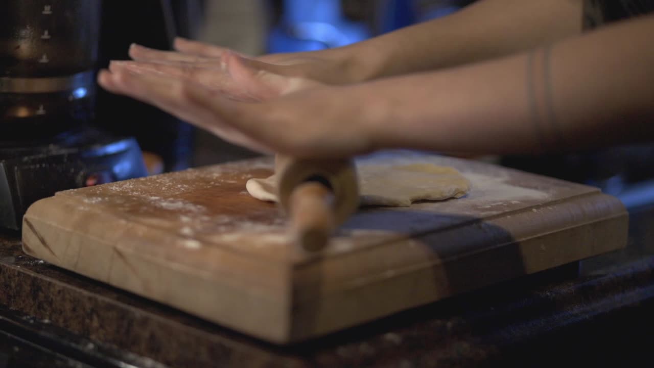 A Baker's Hands Flattening Dough On The Wooden Board With A Rolling Pin - Slowmo