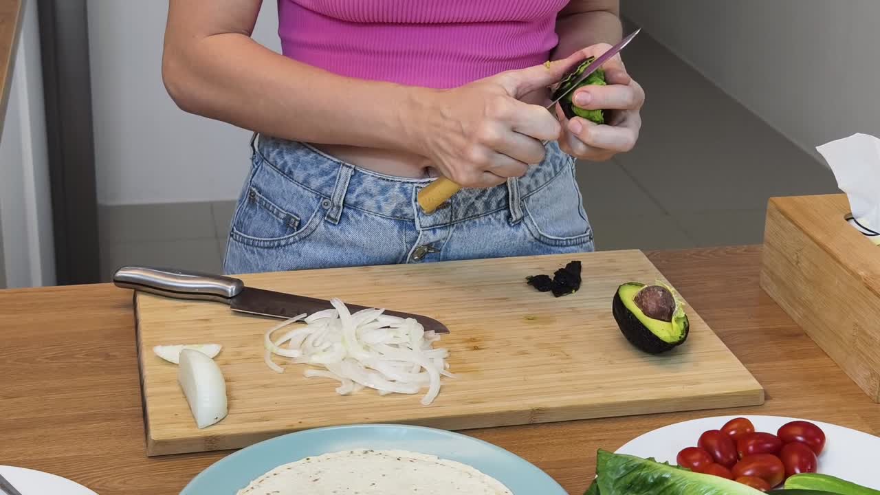 Mujer preparando aguacate y cebolla para una comida