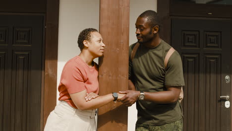 Male-Soldier,-Standing-Outside-Home,-Holding-His-Wife's-Hand-And-Saying-Goodbye-Before-Going-To-Military-Service