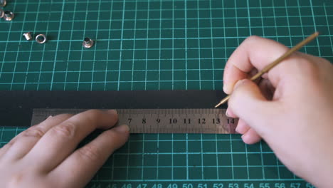 skilled designer draws dots on black leather belt template