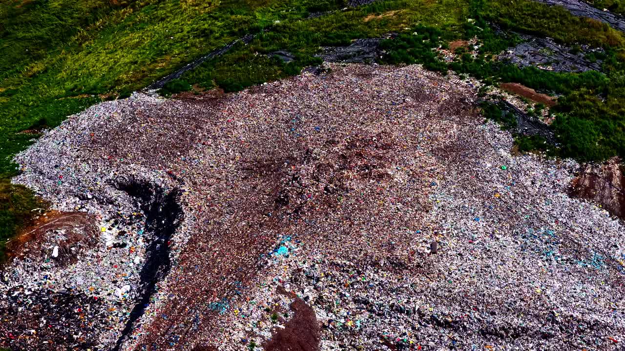 Aerial shot shows massive trash mounds with birds flying above in polluted landscape