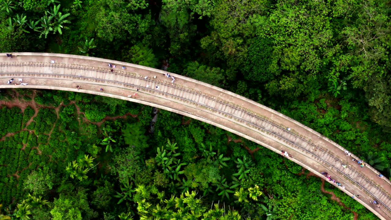 Drone captures a train crossing the famous Nine Arches Bridge in Ella, Sri Lanka, highlighting the iconic landscape of forest and hills