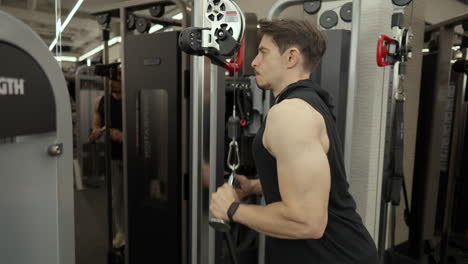 strong, muscular, handsome man bodybuilder performing cable tricep extensions in the gym