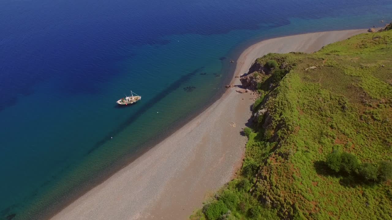 Aerial: A quiet beach with a fishing boat on Lesbos, near Turkey