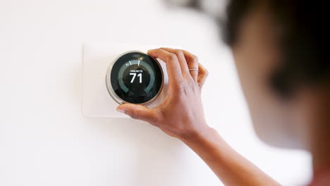 Close-Up-Of-Woman-Setting-Smart-Heating-Thermostat-At-Home