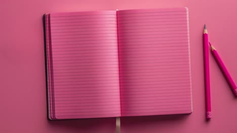 Cuaderno-Abierto-De-Color-Rosa-Con-Lápices-Sobre-Fondo-Rosa