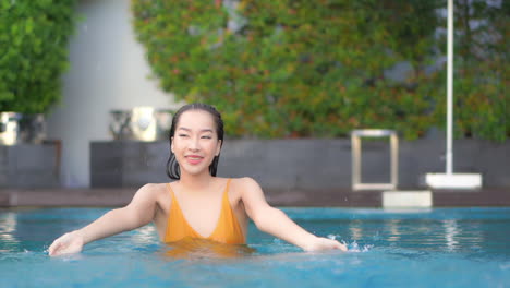 Close-up-of-a-young-woman-in-a-private-resort-pool-is-splashing-water-everywhere