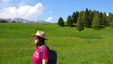 woman with sunglasses walking along a green meadow in alpe di siusi, italy