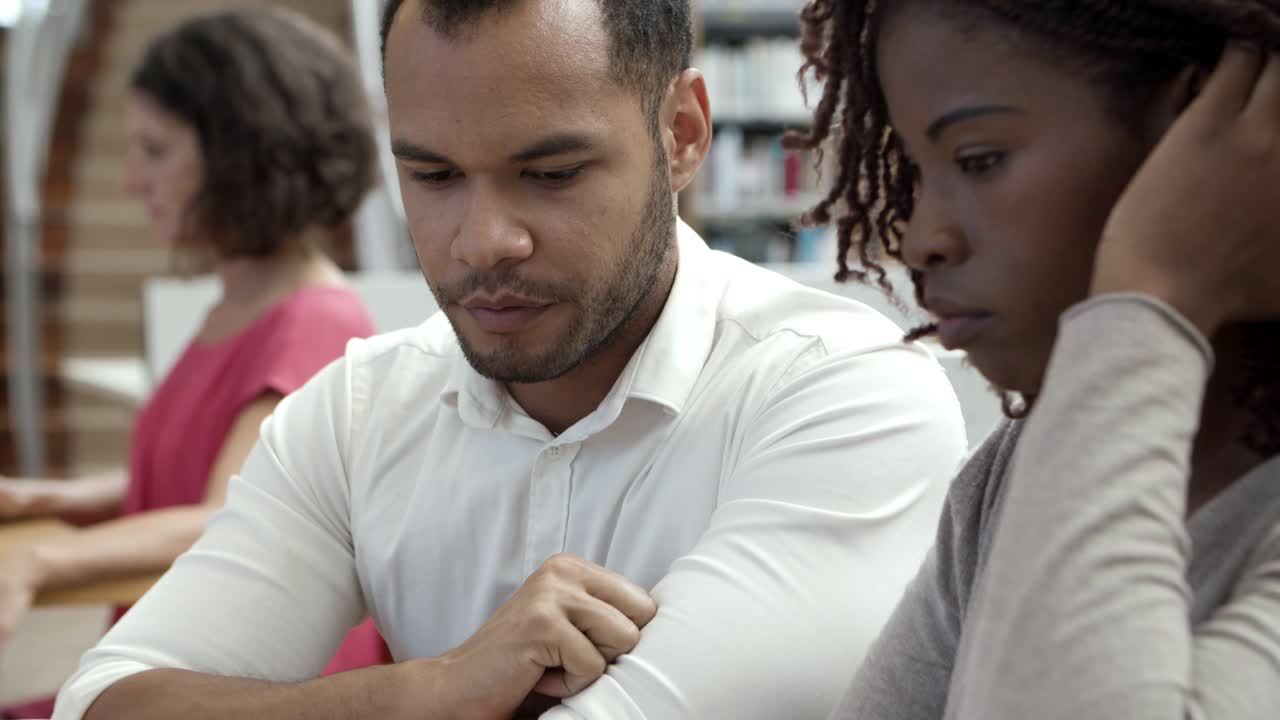 personas pensativas que trabajan juntas con una laptop en la biblioteca