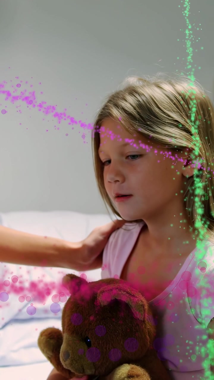 Female child clutching teddy bear on bed while adult placing hand, particles flowing for therapy