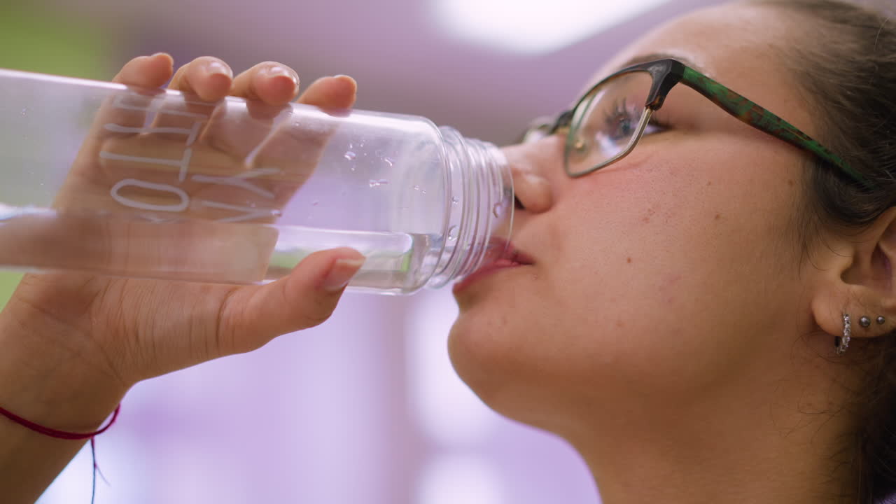 Side view girl standing blurred background showing table chair cloth drinking water feeling relaxed calm wellness hydration balance peaceful lifestyle comfort energy refreshment focus