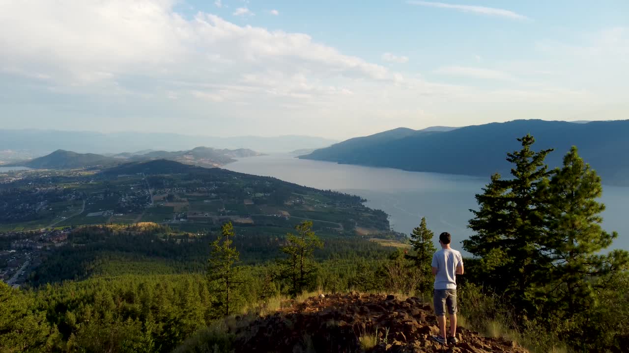 Hiker walks up at Viewpoint in Canadian Mountains overlooking Okanagan Lake and Lakecountry in British Columbia's Interior Region