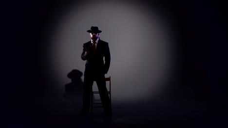 man in suit and fedora posing under spotlight