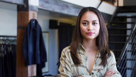 Portrait-Of-Smiling-Female-Owner-Of-Fashion-Store-Standing-In-Front-Of-Clothing-Display