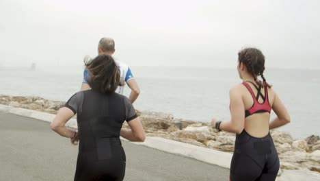 triatletas masculinos y femeninos trotando por el paseo marítimo