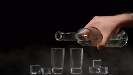 pouring vodka into shot glasses with ice cubes