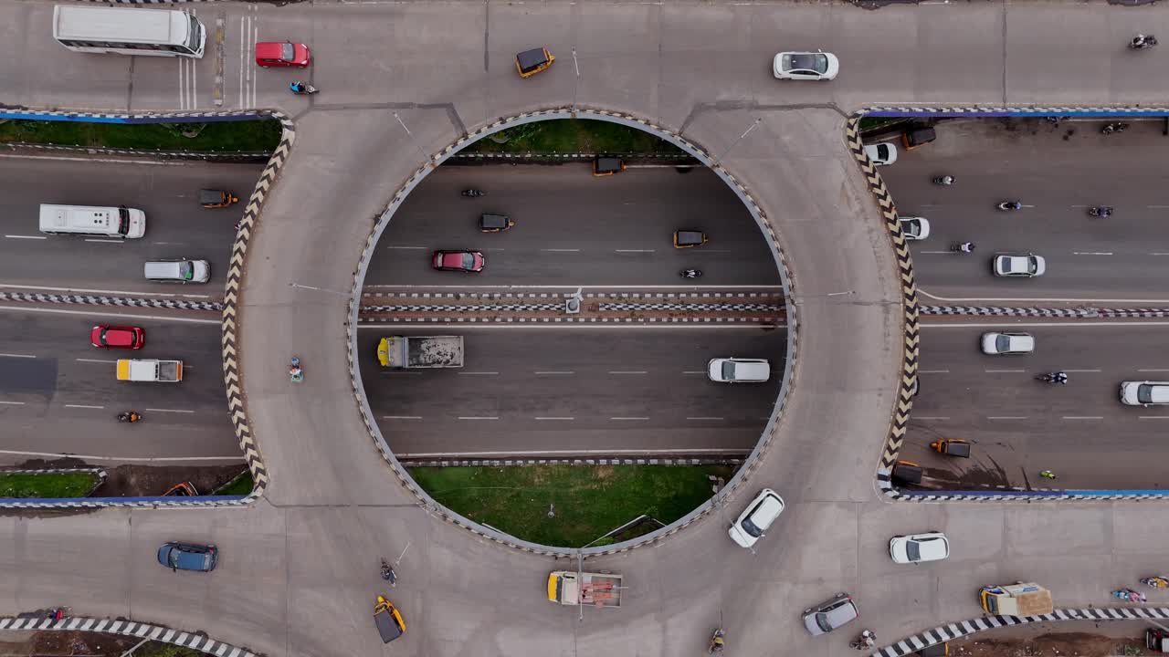 Aerial top shot of a traffic circle showing vehicles navigating the circular intersection.