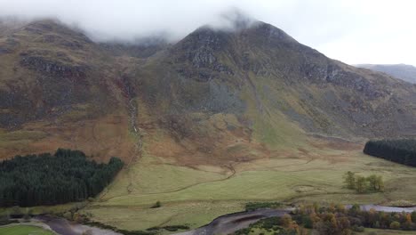 Upward-aerial-view-over-green-hills-and-river-of-Scottish-highlands-misty-and-overcast