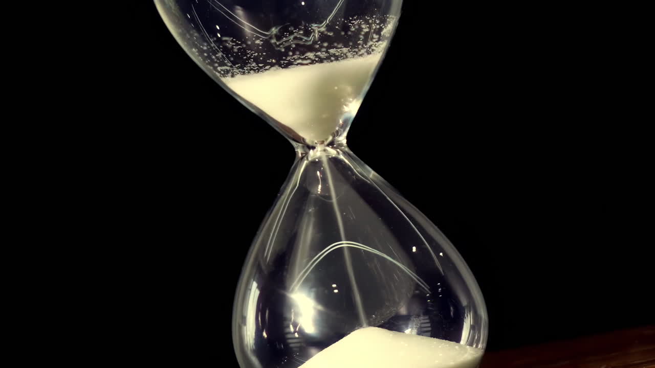 Closeup Fantasy art hourglass on table, sand flowing through the bulb of sandglass on black tone template