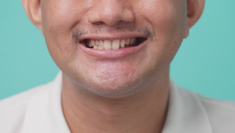 close up of portrait of attractive asian young man toothy smiling and laughing in studio with isolate green screen in background. the man feel happy and cheerful with positive attitude and thinking.