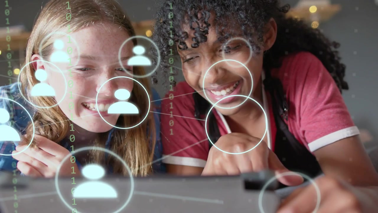 Two teen girls leaning over tablet, one tapping screen exploring growing social avatar network
