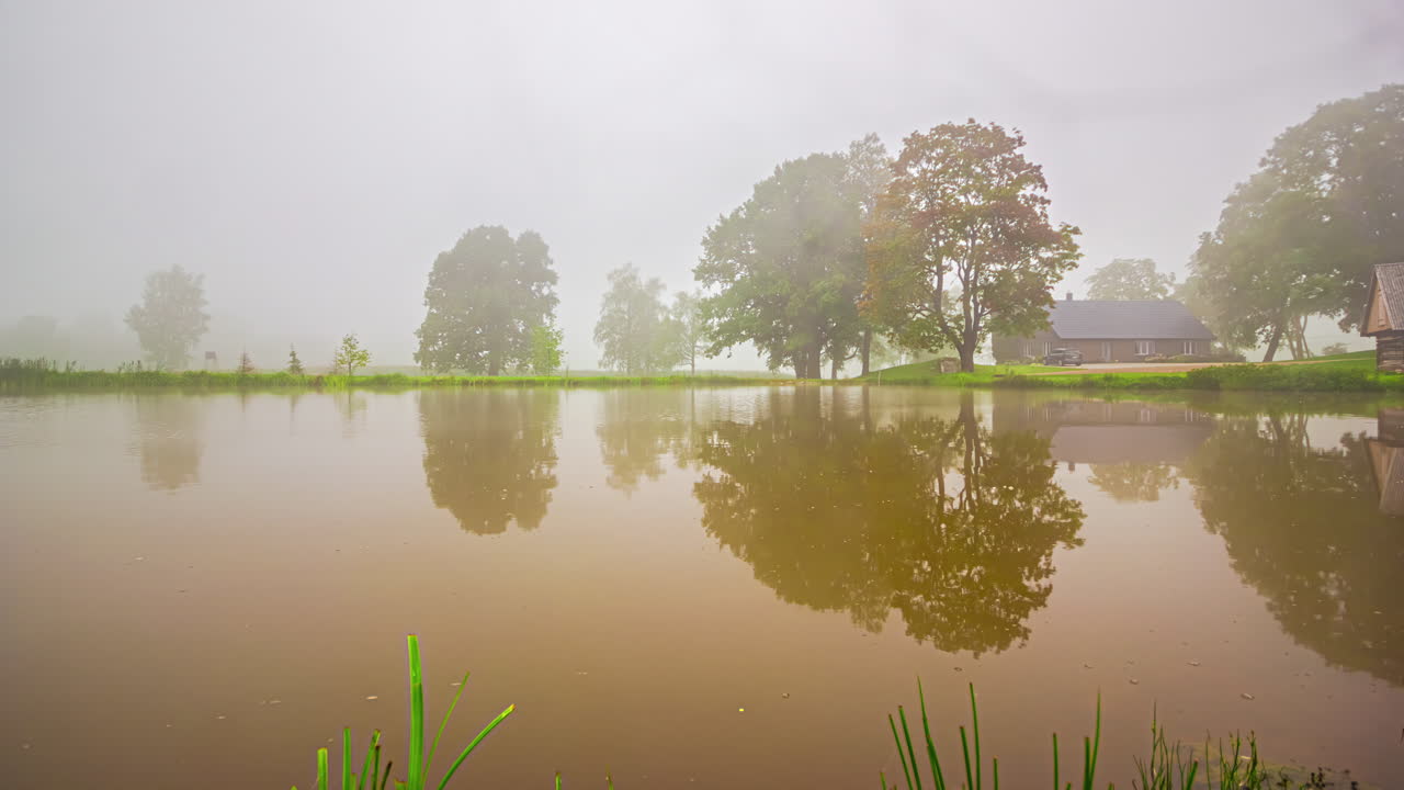 라트비아에서 안개가 형성되는 시골의 호수 위의 타임  ⁇ 스 구름 풍경