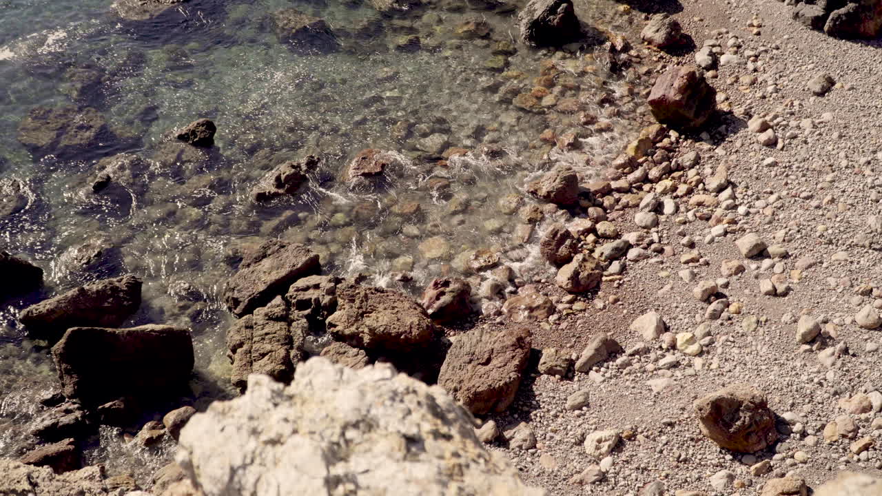 Acqua cristallina che arriva dolcemente su una spiaggia rocciosa in Portogallo.